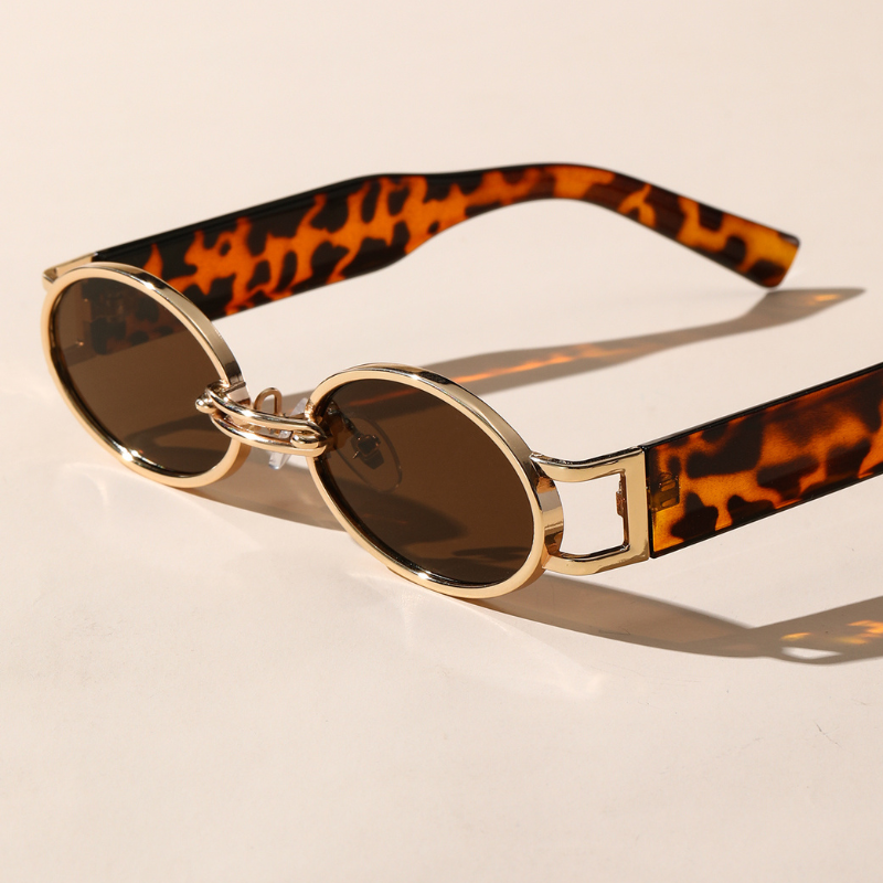 Round retro oval sunglasses with a durable metal frame in gold, brown-tinted UV400 protection lenses, and tortoiseshell-patterned arms, resting on a light surface.