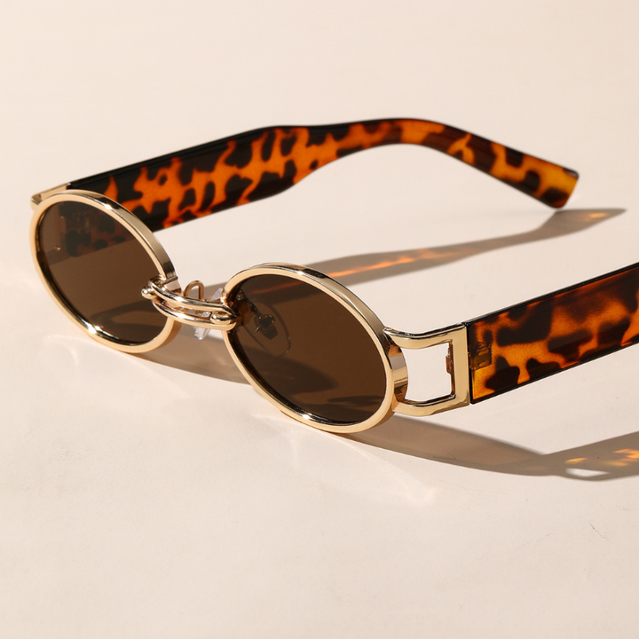 Round retro oval sunglasses with a durable metal frame in gold, brown-tinted UV400 protection lenses, and tortoiseshell-patterned arms, resting on a light surface.