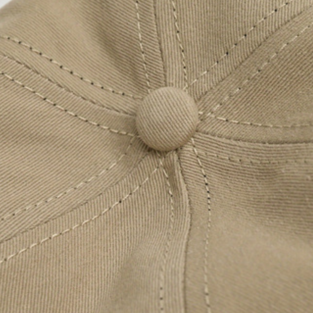 Close-up of the top of a beige wide brim cap made from premium cotton, showing detailed stitching and a button at the center for added sun protection.