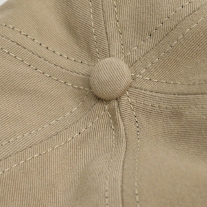 Close-up of the top of a beige wide brim cap made from premium cotton, showing detailed stitching and a button at the center for added sun protection.