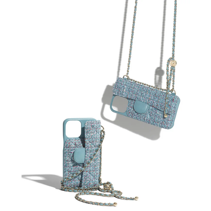 Two stylish phone cases with blue and multicolor woven fabric, featuring small pouches and a stylish chain strap, are displayed against a white background; one is upright while the other hangs elegantly by its chain.