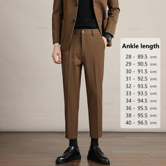 A person in a brown suit and black shoes stands indoors beside a size chart labeled Ankle length, listing pant lengths in centimeters for waist sizes 28 to 40—highlighting Mens Slim Casual Trousers made from premium fabric.