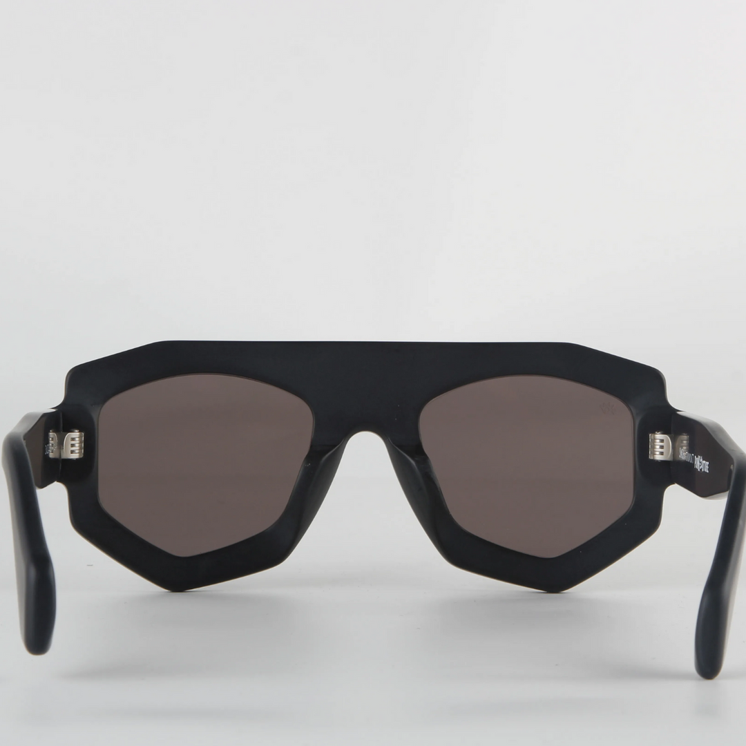 A pair of black, geometric-frame sunglasses crafted from acetate with dark tinted lenses and UV400 protection, shown from the front against a plain white background.
