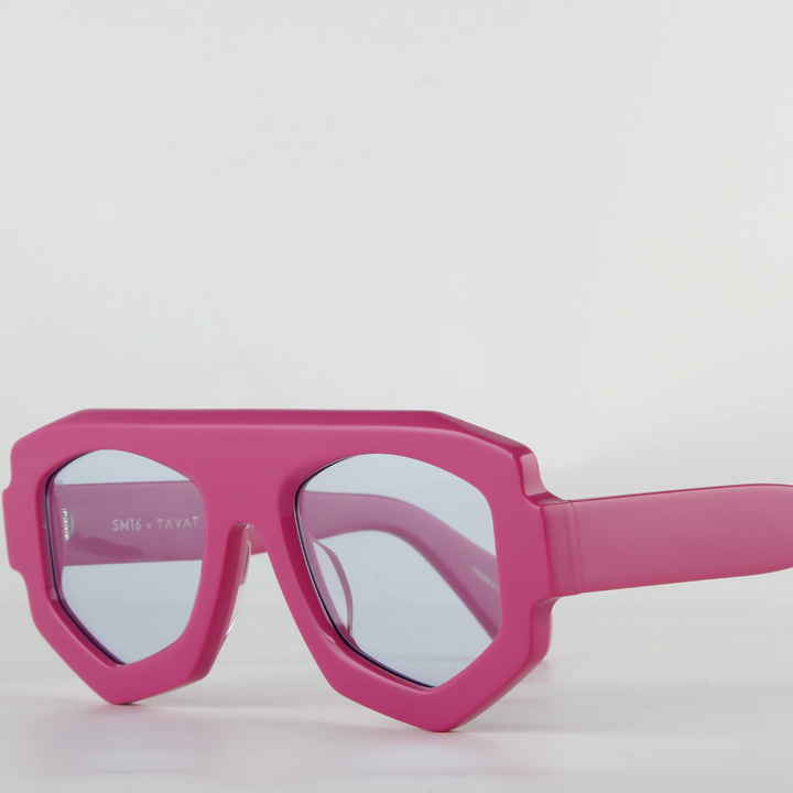 A pair of bold, geometric pink sunglasses with thick acetate frames and blue-tinted lenses featuring UV400 protection, set against a plain white background.
