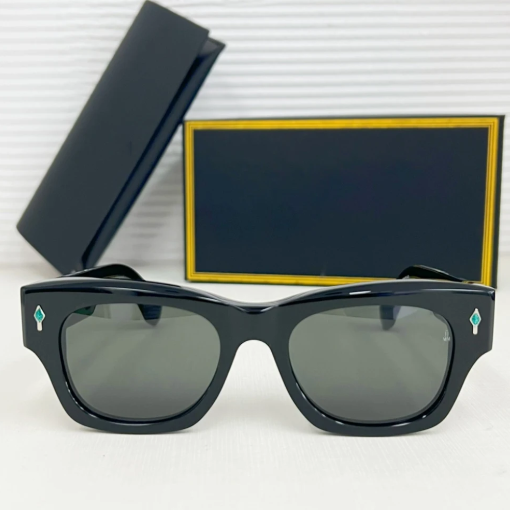 A pair of vintage-inspired black rectangular sunglasses with dark lenses is displayed in front of a black and gold-trimmed case and box. The frames feature small turquoise diamond-shaped accents and offer UV400 protection.