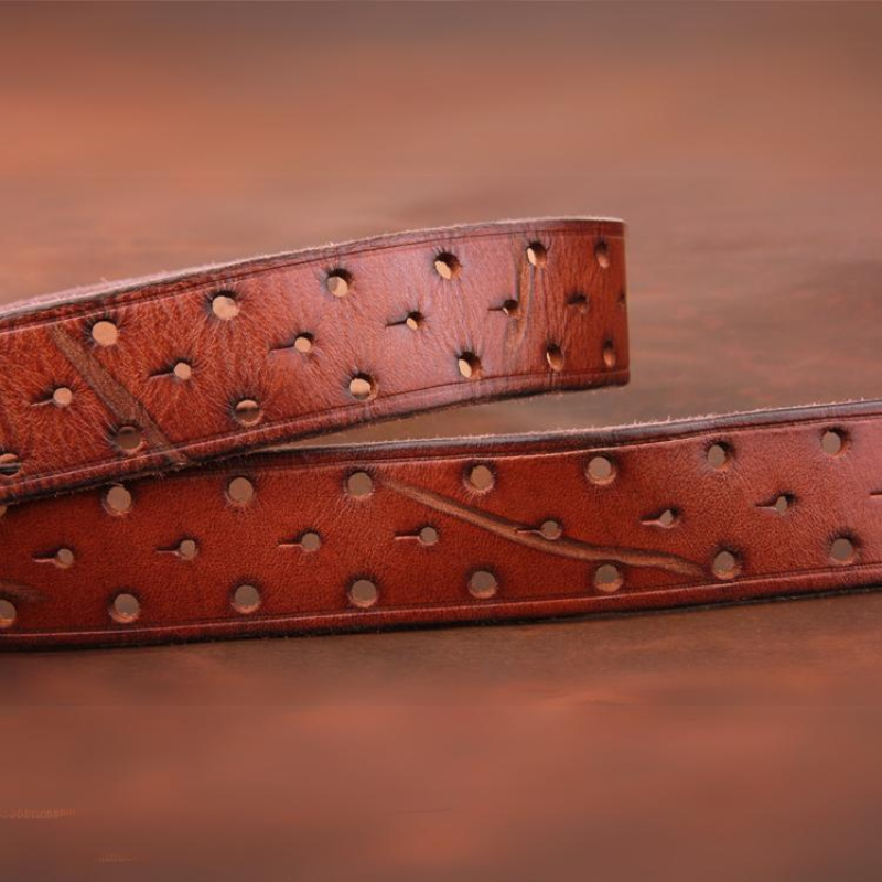 A close-up of a handcrafted belt made from premium leather, with evenly spaced round holes and visible stitching, set against a blurred brown background.