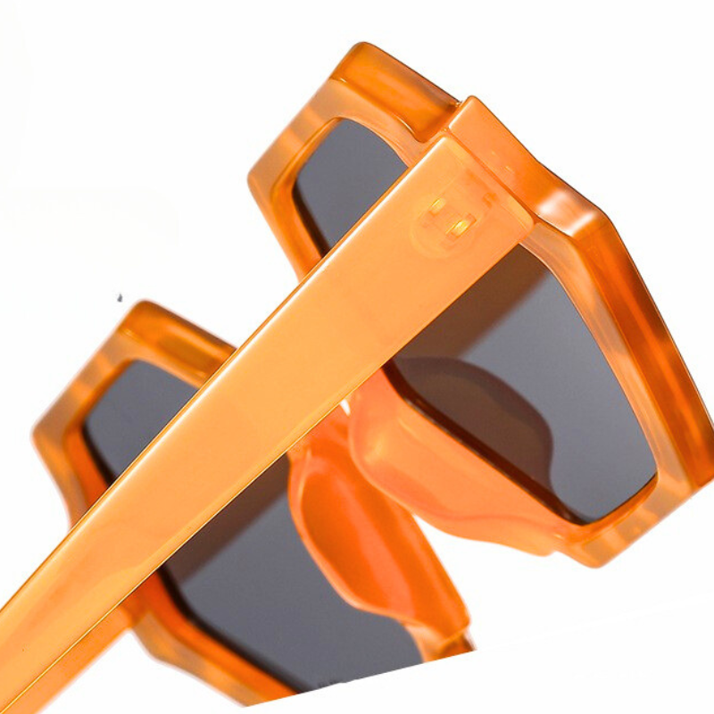 Close-up of trend-forward orange sunglasses with dark lenses and a bold hexagonal frame, shown against a white background. These stylish sunglasses offer UV400 protection and feature thick, angled frames for a modern look.