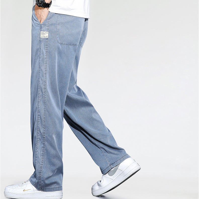 A person wearing Summer Loose Men Jeans in light blue and white Nike sneakers is shown walking, photographed from the waist down against a plain white background.