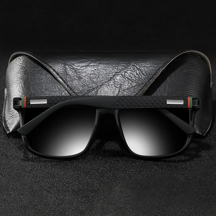 A pair of stylish UV400 sunglasses with gradient lenses rest in front of a black textured leather case, set against a dark background.