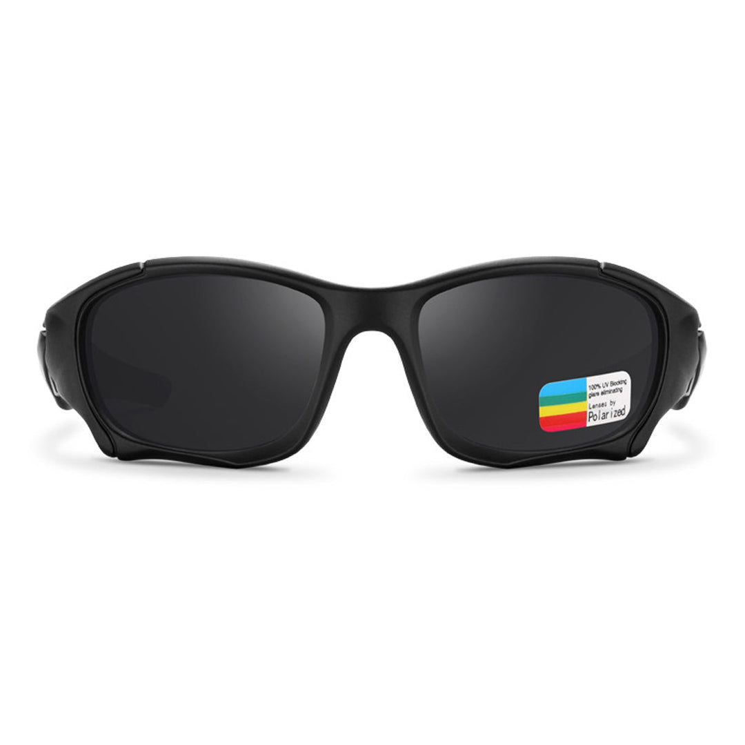 A pair of black wraparound sports sunglasses with dark lenses, shown from the front. A small rectangular sticker with colorful stripes and text is attached to one lens.