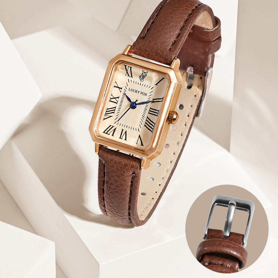 A rectangular face watch with a white dial, Roman numerals, and a genuine leather strap is displayed on a white geometric background. An inset highlights the watch’s silver buckle.