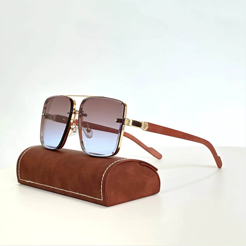 Stylish vintage sunglasses with brown gradient lenses, gold rims, and wooden arms rest on a brown leather case with white stitching, set against a plain white background.