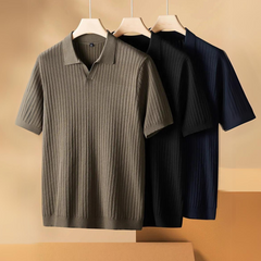 Three ribbed knit polo shirts in olive, black, and navy blue hang on wooden hangers against a neutral beige background—perfect lightweight polos for the urban professional.
