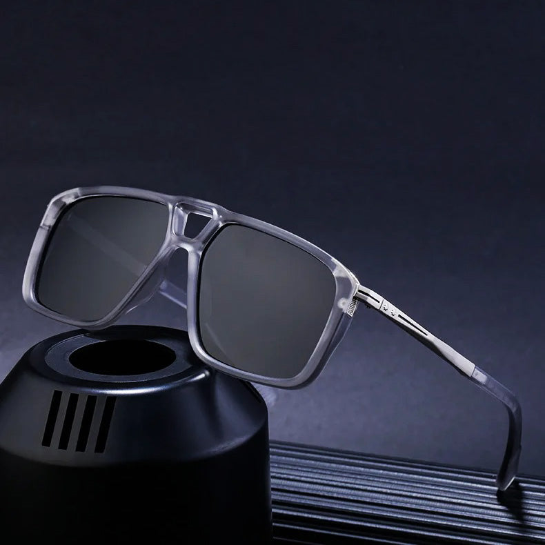 A pair of square, translucent gray polarized sunglasses with dark lenses is displayed, resting on a black cylindrical stand against a dark background.