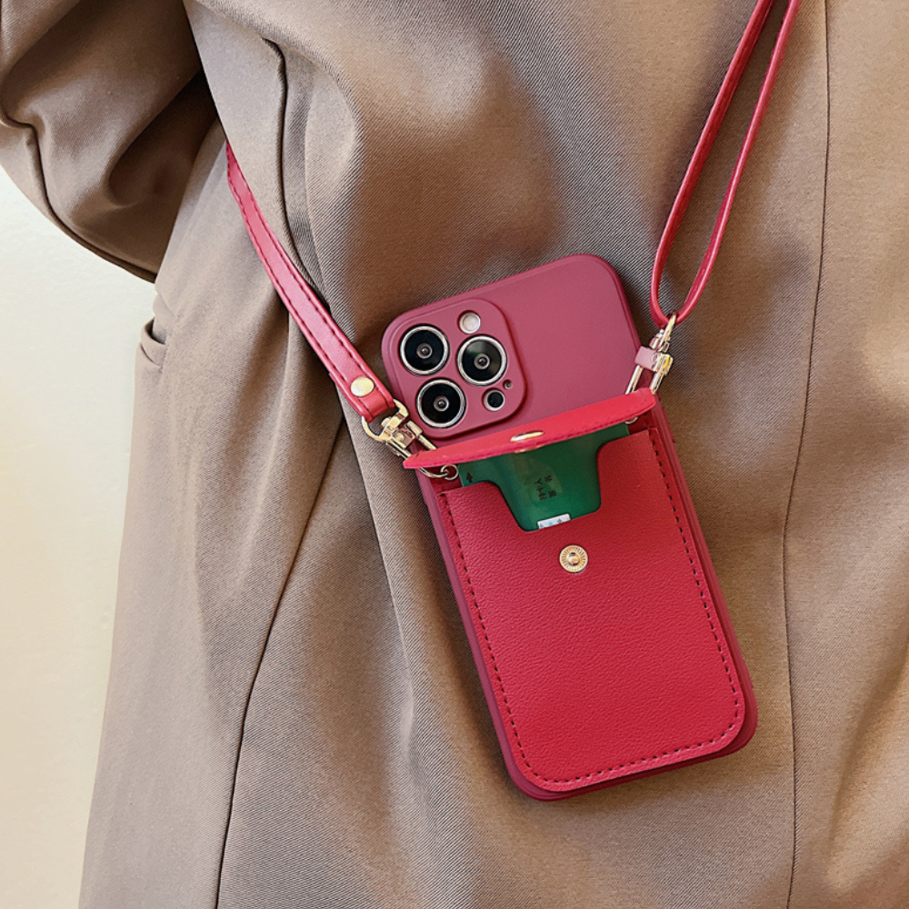 A person wearing a tan jacket carries a smartphone in a red phone case wallet with a secure cardholder and front pocket holding a green item. The case, featuring three cameras, includes a leather detachable strap for convenience.