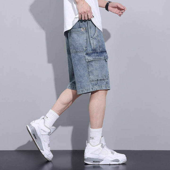 A person wearing a white t-shirt, mens denim shorts with an elastic waist, white crew socks, and white sneakers stands in profile against a plain gray background.
