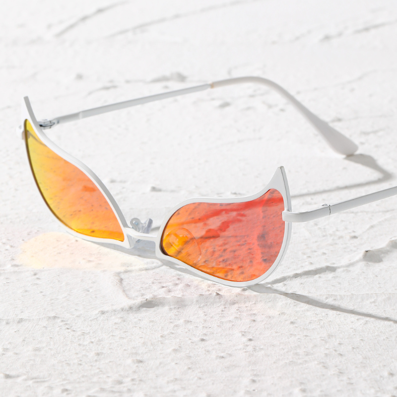 White-framed sunglasses with orange-tinted, flame-shaped lenses and a lightweight frame rest on a textured white surface, casting a shadow.