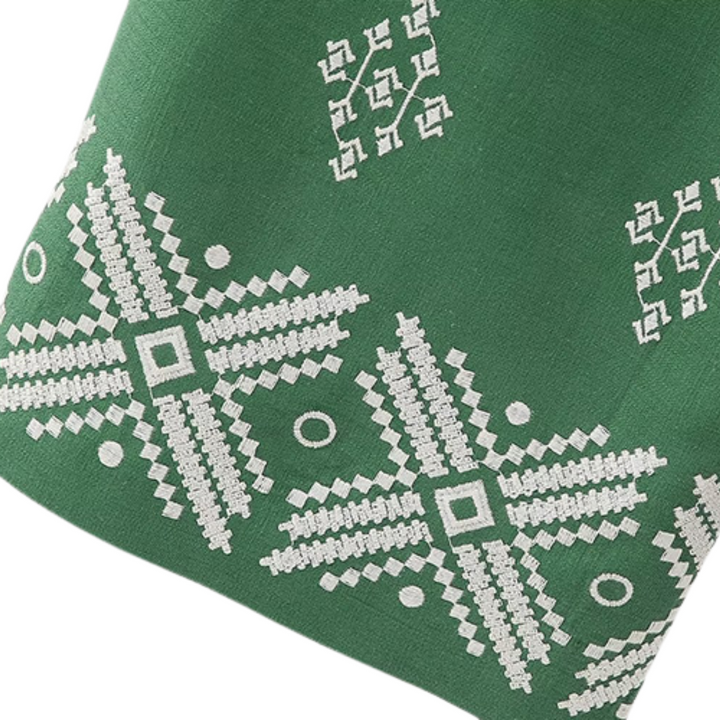 Green fabric with white embroidered geometric patterns, including star-like shapes and circles, creates a decorative and intricate design—perfect for stylish boho chic pants.