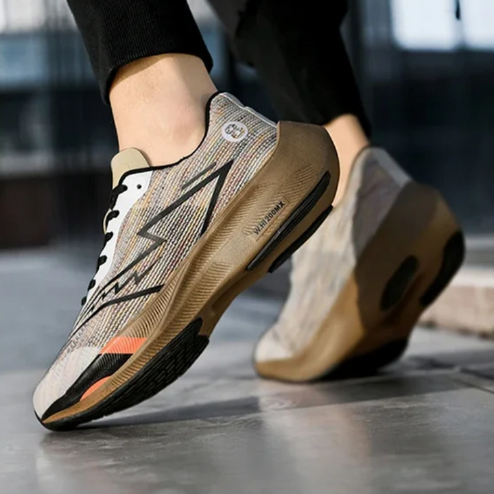 Close-up of a person wearing light-colored athletic sneakers with black accents and thick soles, featuring a shock-absorbing sole. The focus is on the shoes, showcasing their lightweight construction, design, and texture.