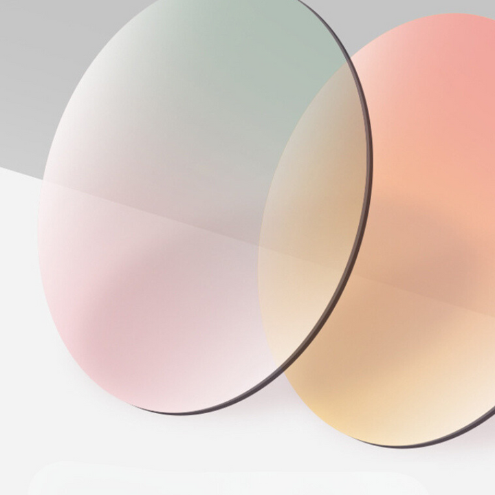 Two thin, round optical lenses with a slight tint—one with a pinkish hue, the other with a yellowish tint—overlap against a light gradient background, showcasing a trend-forward look.