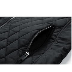 Close-up of a black quilted slim-fit jacket featuring a zippered pocket. The zipper is partially open, revealing the inner lining, and the diamond stitching pattern highlights its wind-resistant fabric.