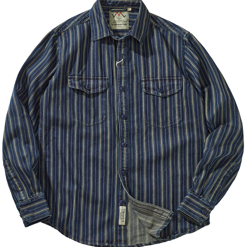 A striped denim shirt with blue, white, and gold vertical stripes, two chest pockets with button flaps, and a collar. The relaxed-fit button-down is laid flat with the bottom slightly folded to reveal the inner tag.