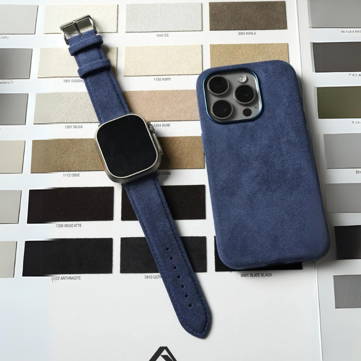 A blue smartwatch with a stainless steel buckle and a blue phone case are placed on a color swatch chart featuring various neutral shades, including grays, beiges, and browns.