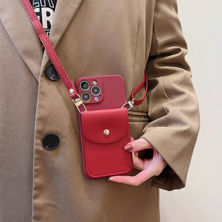 A person in a tan coat holds a smartphone with a red phone case wallet that includes a matching pouch and leather detachable strap, blending style, functionality, and a secure cardholder design.