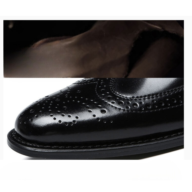 A shiny black premium leather brogue dress shoe with decorative perforations, shown from the side, part of the upper section out of frame.