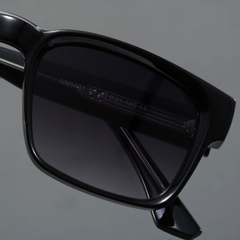 Close-up of the right side of black rectangular sunglasses with durable frames and dark tinted lenses, featuring visible frame details and a modern design, set against a plain gray background.