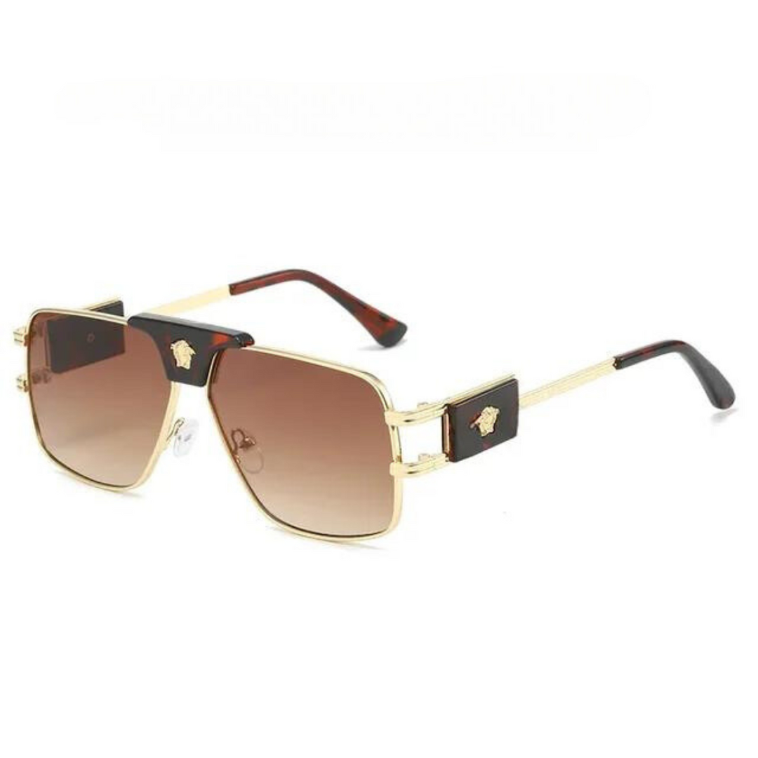 Gold-rimmed square bold sunglasses with brown gradient lenses, featuring premium metal frames and black and gold decorative accents on the temples. Stylish and modern, they offer UV400 protection for your eyes.