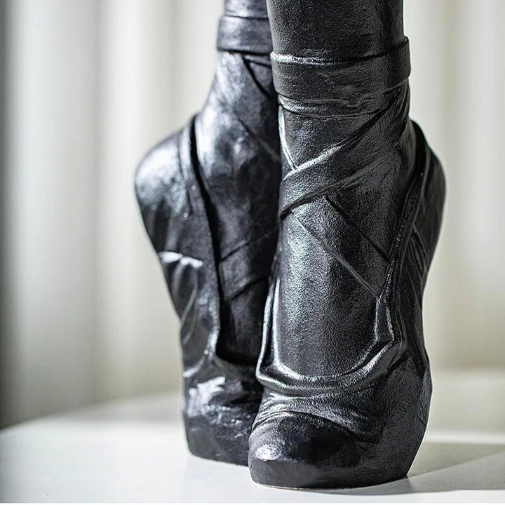 Close-up of a pair of black wedge-heeled boots with a futuristic design and angular, sculpted shapes, shown against a neutral background that evokes contemporary chic décor.