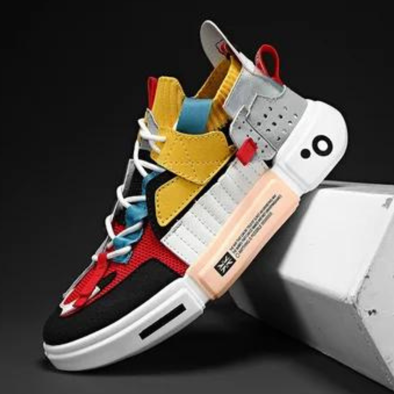 A colorful Extreme VS7 sneaker featuring red, yellow, blue, black, white, and gray panels with a chunky white sole and unique geometric design—these lightweight breathable sneakers are displayed on a white block against a dark background.