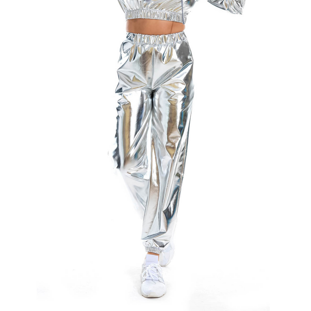 A person wearing shiny silver metallic pants with an elastic high waist and white shoes is walking, their upper body partially out of frame against a white background.