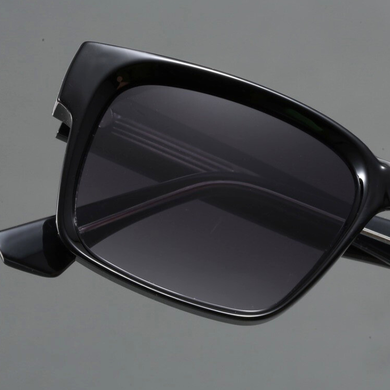 Close-up of black rectangular sunglasses with modern design and dark tinted lenses, crafted with durable frames and UV400 protection, shown against a plain gray background.