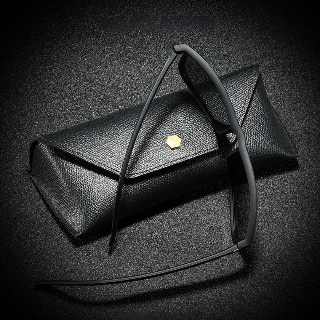 A pair of black-rimmed eyeglasses rests against a textured black eyeglass case with a small gold hexagonal emblem, all set on a black, slightly sparkly surface—perfect for storing your stylish sunglasses.