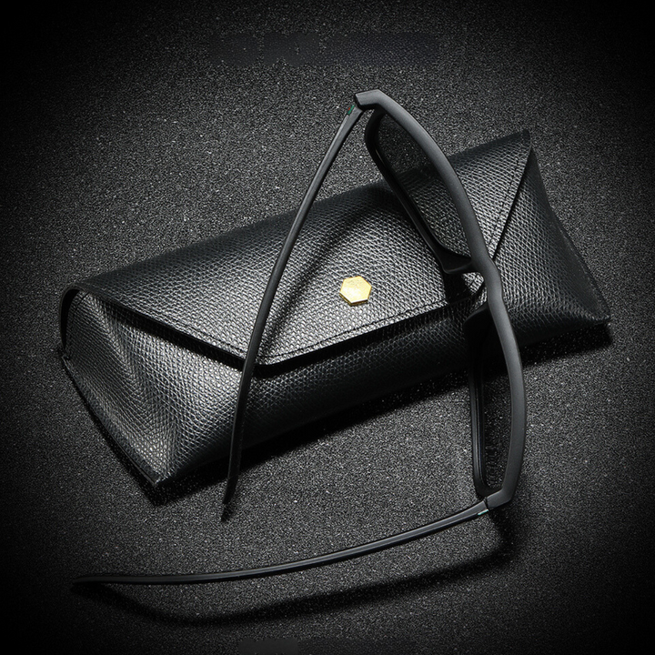 A pair of black-rimmed eyeglasses rests against a textured black eyeglass case with a small gold hexagonal emblem, all set on a black, slightly sparkly surface—perfect for storing your stylish sunglasses.