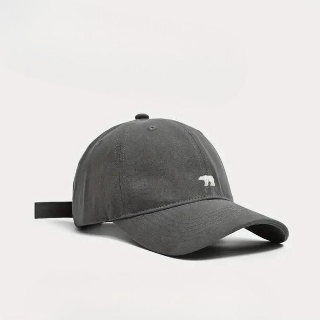 A dark gray premium cotton baseball cap with a curved brim and a small white polar bear embroidered on the front, shown against a plain white background.