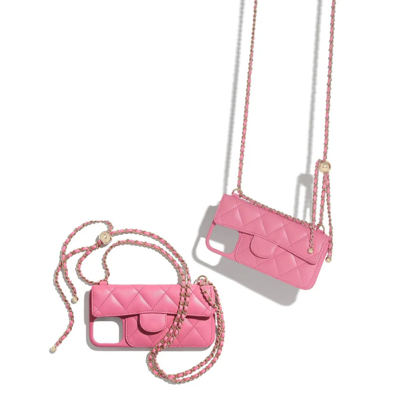 Two pink quilted phone cases with stylish chain straps rest on a white surface. One leather phone case lies flat, while the other hangs diagonally, both casting soft shadows.