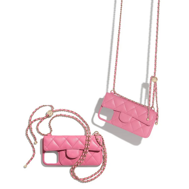Two pink quilted phone cases with stylish chain straps rest on a white surface. One leather phone case lies flat, while the other hangs diagonally, both casting soft shadows.