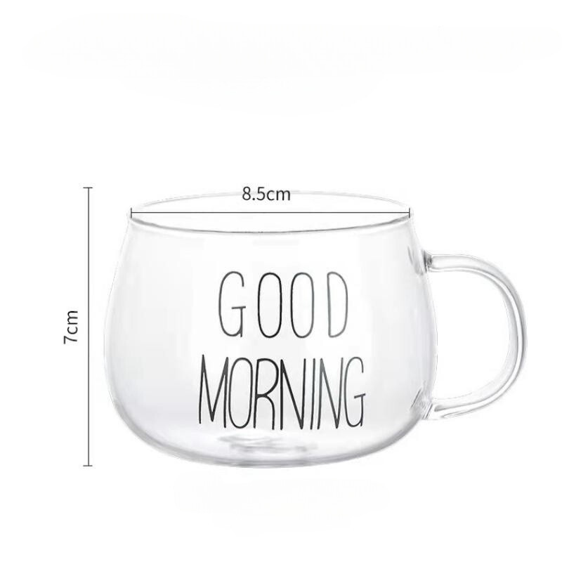 A clear glass mug with an ergonomic handle and GOOD MORNING written in black letters. Made from heat-resistant glass, the mug measures 8.5 cm in diameter and 7 cm in height, with a handle on the right side.