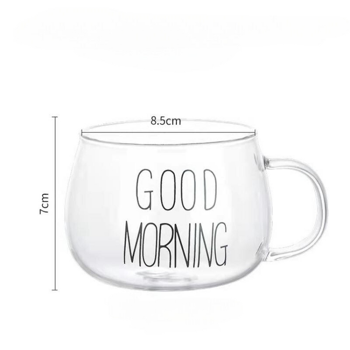 A clear glass mug with an ergonomic handle and GOOD MORNING written in black letters. Made from heat-resistant glass, the mug measures 8.5 cm in diameter and 7 cm in height, with a handle on the right side.