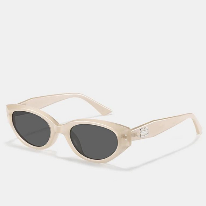 Cream-colored cat-eye sunglasses with dark lenses and a thick, translucent acetate frame. The left arm features a small, subtle raised DG logo near the hinge. Stylish and modern, these shades offer reliable UV400 protection. Displayed on a plain white background.