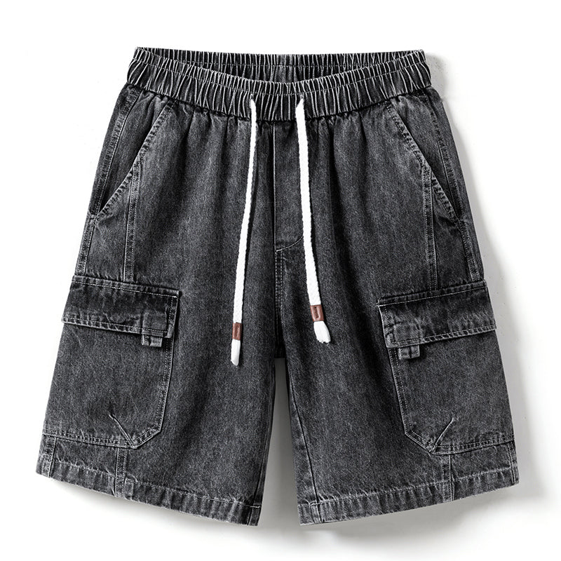 A pair of mens denim shorts in black with an elastic waist, white drawstring, side pockets, and flap pockets on each leg—laid flat on a white background.