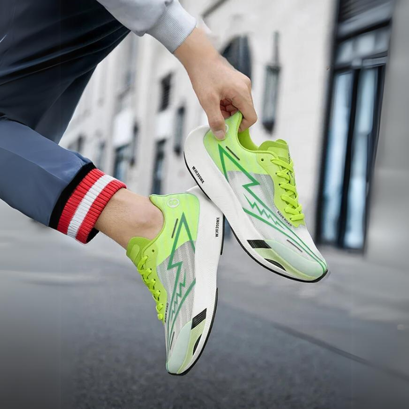 A person wearing bright green and white running shoes with a lightning bolt design is crouching on a city sidewalk, holding one shoe to show off its shock-absorbing sole and impressive Super foam Rebound cushioning.