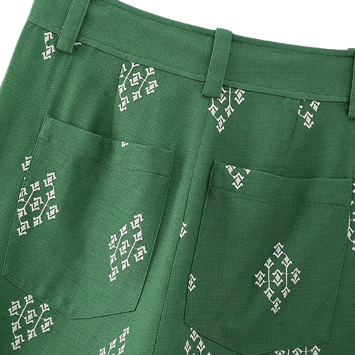 Green boho chic pants with white geometric patterns and two back pockets, shown from the waist down. The fabric has a subtle texture, and these wide-leg trousers feature handy belt loops for a relaxed yet stylish look.