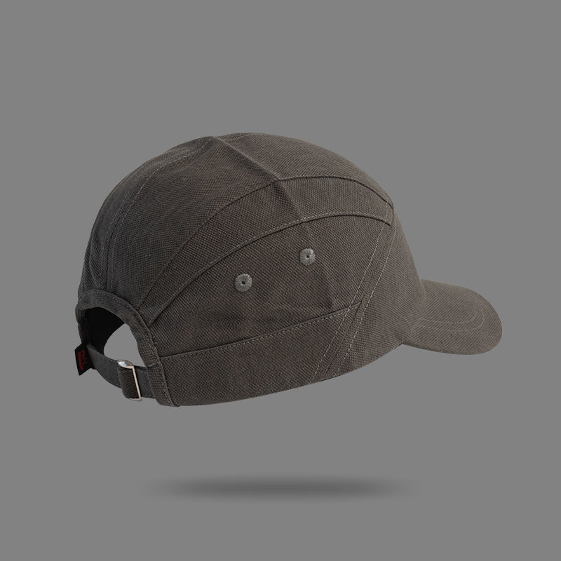 A dark gray unisex cap with visible stitching, metal eyelets, and an adjustable strap at the back, designed in a Japanese-style peaked cap silhouette and displayed against a plain gray background.