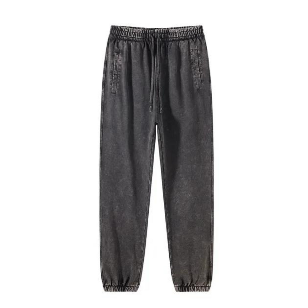 Black, acid-washed jogger pants with an elastic waistband, drawstring, deep pockets, and tapered cuffs, displayed against a white background.