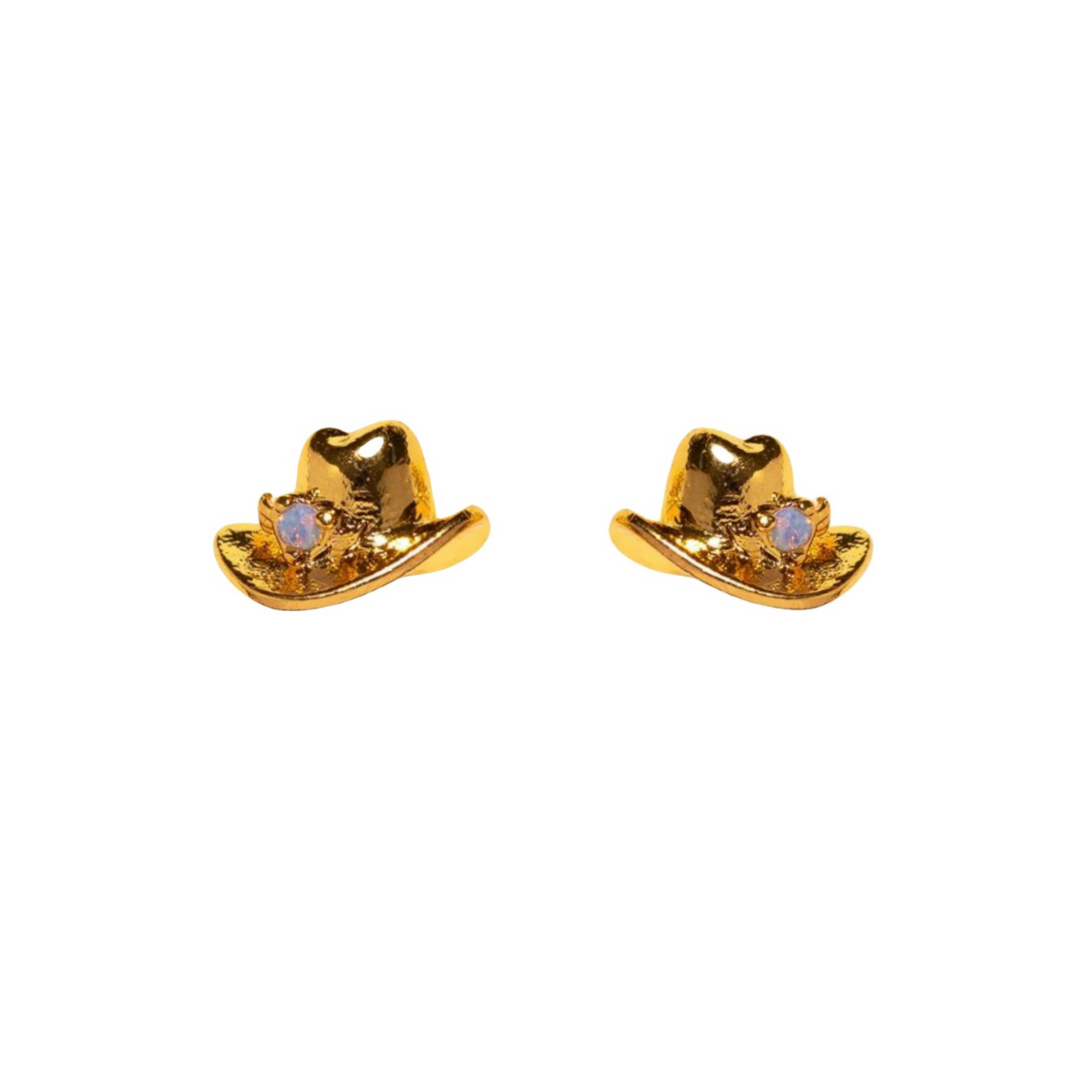 A pair of gold-colored cowboy hat-shaped statement earrings, each featuring a small round white gemstone on the front.