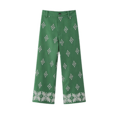 Green wide-leg trousers featuring a white diamond and geometric pattern throughout, with a more intricate design near the hem. These boho chic pants have belt loops, a button, and a zipper fly.